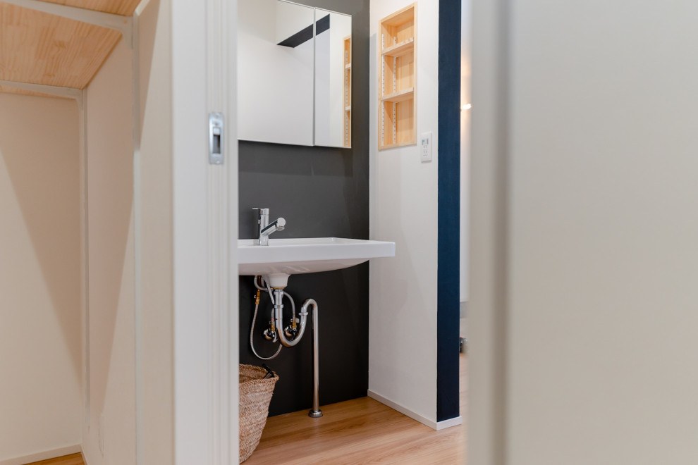 Inspiration pour un WC et toilettes minimaliste avec un mur noir, un sol en bois brun, un sol beige, meuble-lavabo sur pied, un plafond en papier peint et du lambris.