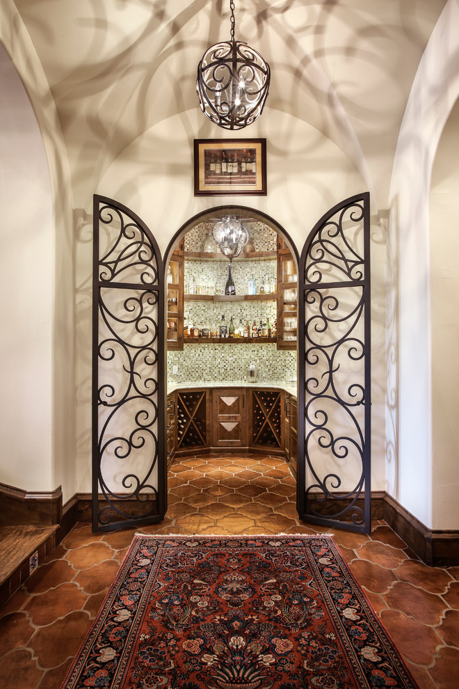 This is an example of a mediterranean wine cellar in Dallas with terra-cotta floors and diamond bins.