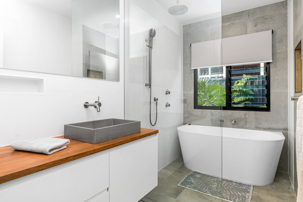 Inspiration for a contemporary wet room bathroom in Gold Coast - Tweed with flat-panel cabinets, white cabinets, a freestanding tub, gray tile, a vessel sink, wood benchtops, grey floor, an open shower, brown benchtops, a double vanity and a floating vanity.