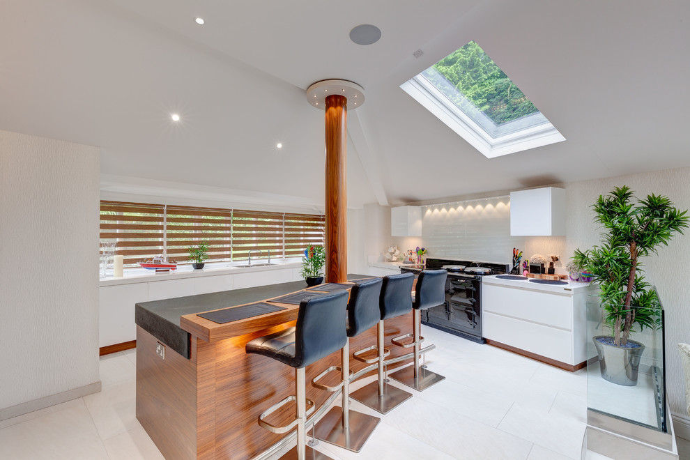 Photo of a mid-sized contemporary kitchen in Cheshire with flat-panel cabinets, white splashback, travertine floors, with island, white floor, an undermount sink, white cabinets and black appliances.