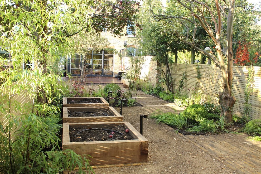 This is an example of a mid-sized traditional backyard partial sun formal garden for summer in London with brick pavers.