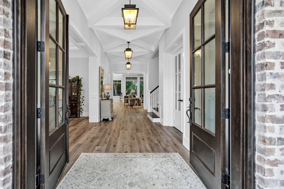 Design ideas for a large foyer in Houston with white walls, medium hardwood floors, a double front door, a brown front door, brown floor and coffered.