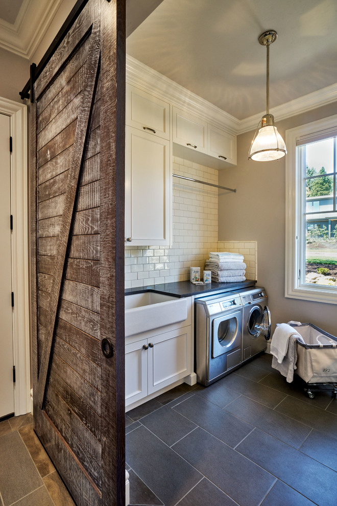 Inspiration for a large traditional dedicated laundry room in Portland with a farmhouse sink, recessed-panel cabinets, white cabinets, quartz benchtops, grey walls, a side-by-side washer and dryer, vinyl floors and grey floor.