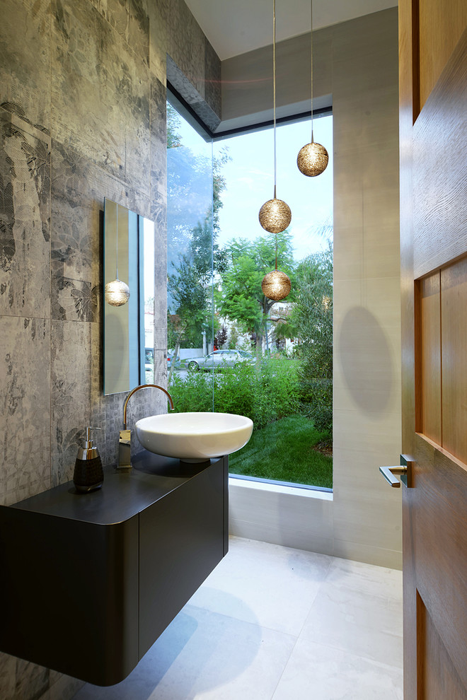 Inspiration for a mid-sized contemporary powder room in Los Angeles with a vessel sink, gray tile, grey walls, flat-panel cabinets, black cabinets, cement tile and solid surface benchtops.