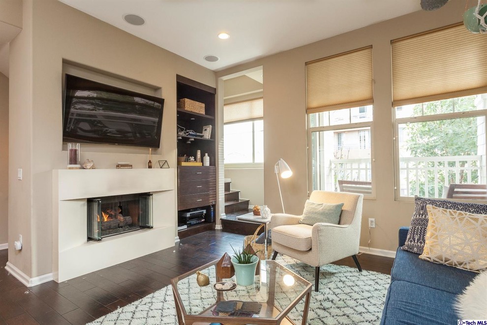 Design ideas for a small eclectic enclosed living room in Los Angeles with white walls, laminate floors, a standard fireplace, a built-in media wall and brown floor.