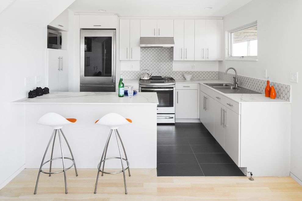 Inspiration for a small contemporary l-shaped kitchen in Boston with a double-bowl sink, flat-panel cabinets, white cabinets, solid surface benchtops, grey splashback, porcelain splashback, stainless steel appliances, porcelain floors and a peninsula.