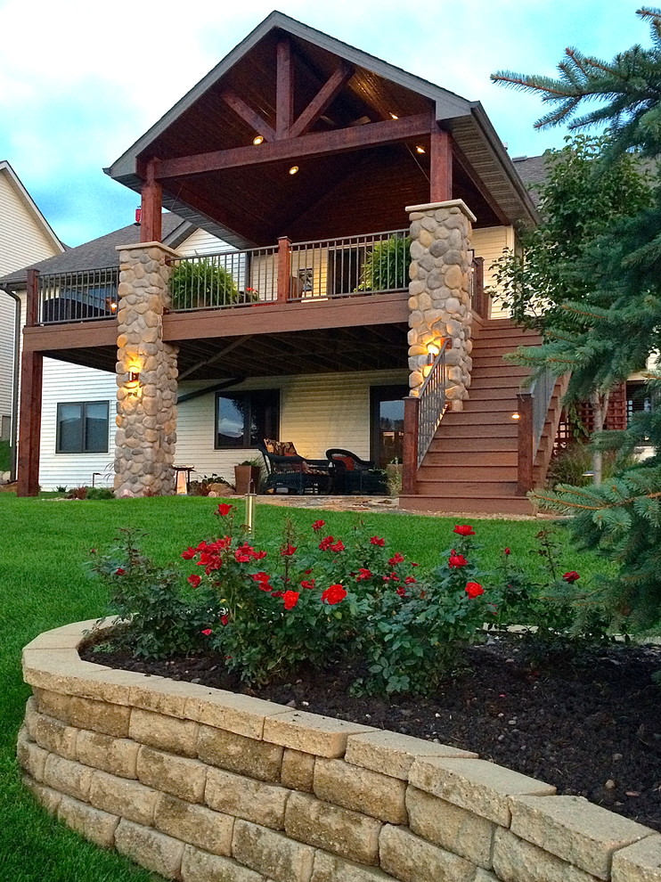 This is an example of a large traditional backyard deck in Other with a roof extension.
