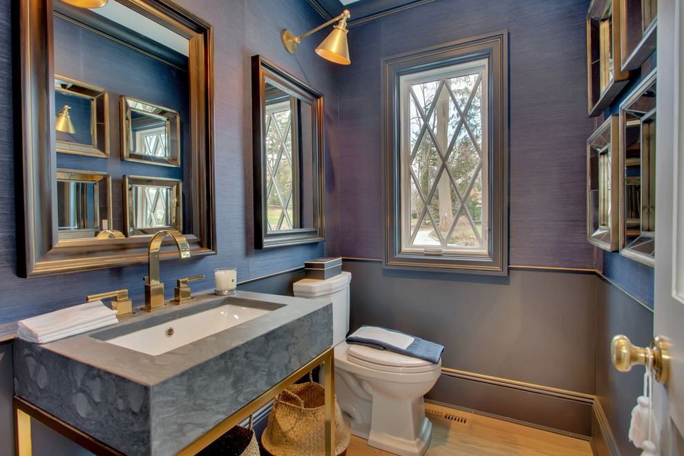 Photo of a mid-sized transitional powder room in New York with a two-piece toilet, blue walls, light hardwood floors, a drop-in sink and brown floor.