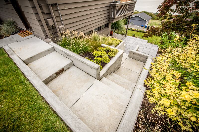 This is an example of a contemporary backyard garden in Seattle with a retaining wall and concrete pavers.