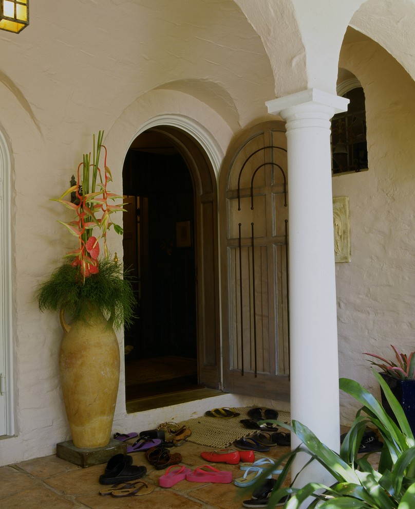 Photo of a tropical entryway in Hawaii with a single front door and a dark wood front door.