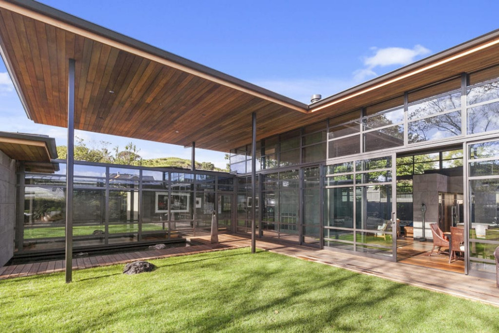Mittelgroßes, Einstöckiges Asiatisches Einfamilienhaus mit Steinfassade, grauer Fassadenfarbe, Flachdach und braunem Dach in Auckland