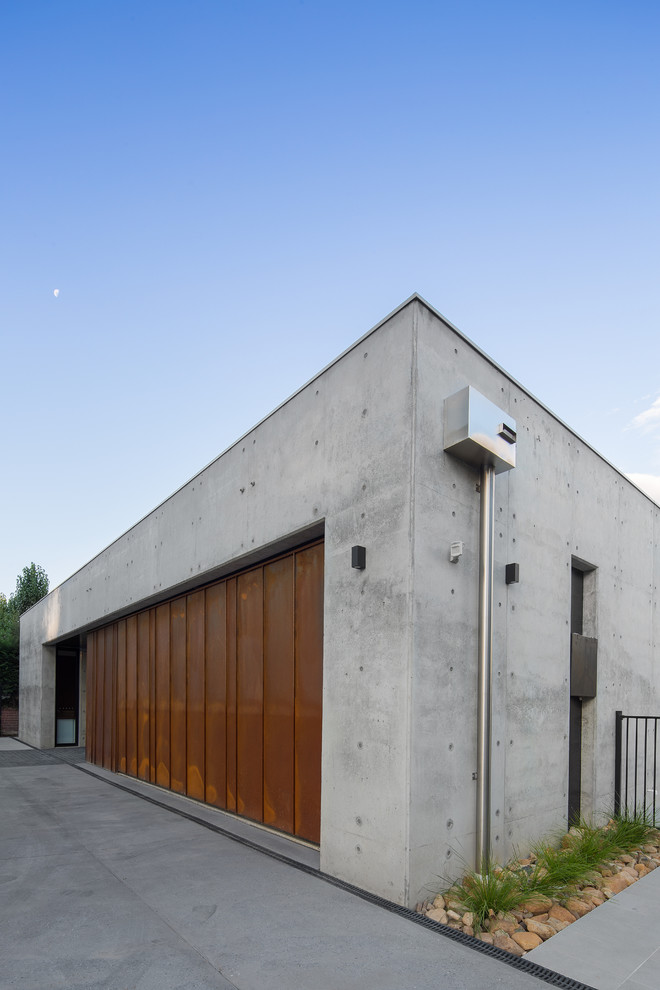 Design ideas for a mid-sized contemporary two-storey concrete grey house exterior in Other with a flat roof and a metal roof.