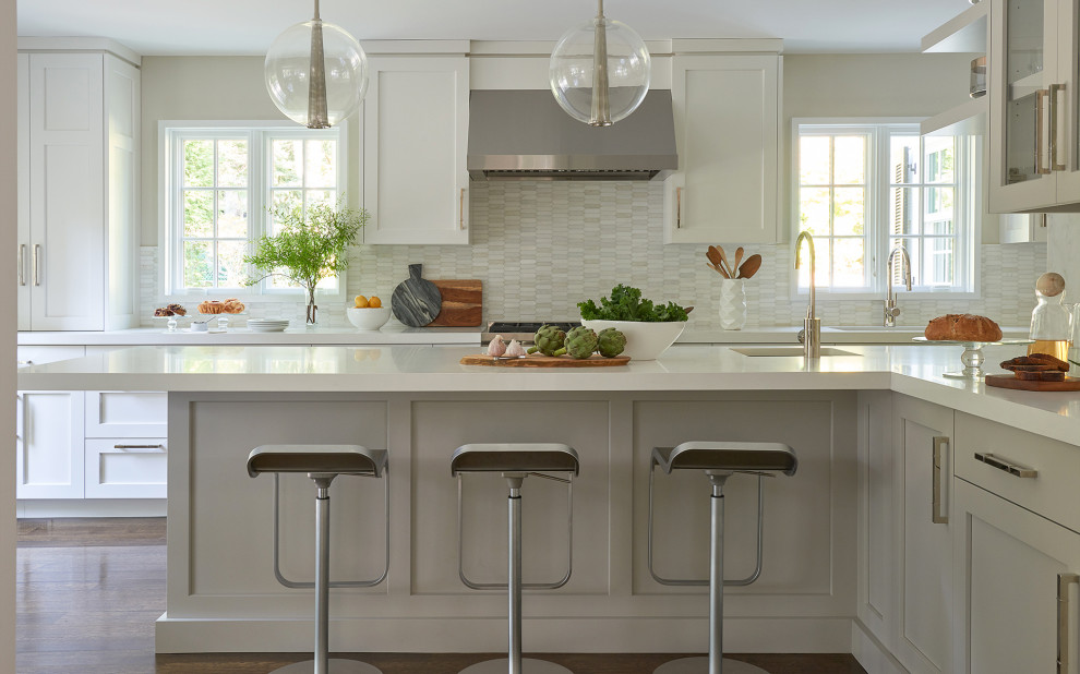 Inspiration for a transitional l-shaped dark wood floor and brown floor kitchen remodel in New York with an undermount sink, shaker cabinets, white cabinets, white backsplash, mosaic tile backsplash, stainless steel appliances, a peninsula and white countertops