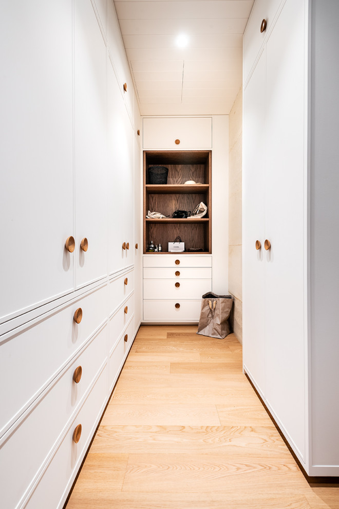 Idéer för att renovera en mellanstor funkis garderob för könsneutrala, med skåp i shakerstil, vita skåp, ljust trägolv och beiget golv