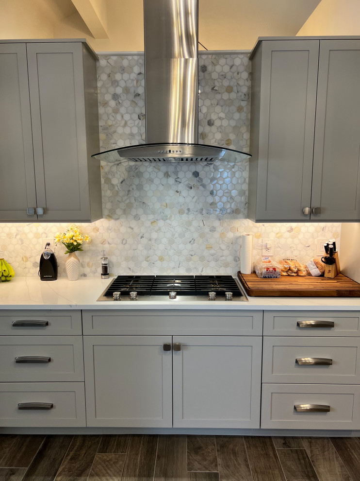 Inspiration for a large transitional u-shaped porcelain tile and brown floor eat-in kitchen remodel in Austin with an undermount sink, shaker cabinets, gray cabinets, quartz countertops, white backsplash, marble backsplash, stainless steel appliances, an island and white countertops