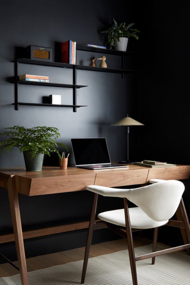 Mittelgroßes Arbeitszimmer mit Arbeitsplatz, schwarzer Wandfarbe, braunem Holzboden und freistehendem Schreibtisch in Wiltshire