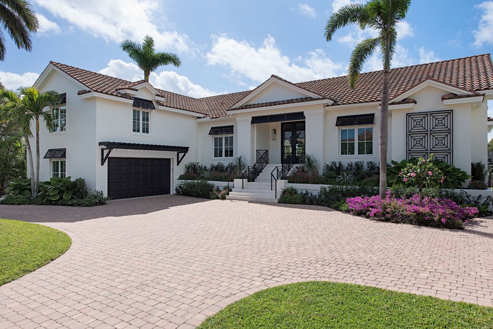 This is an example of a transitional two-storey stucco white house exterior in Miami with a gable roof and a tile roof.