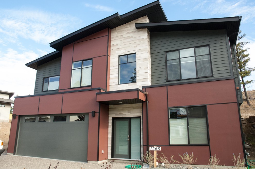 This is an example of a modern two-storey red exterior in Vancouver with stone veneer and a flat roof.
