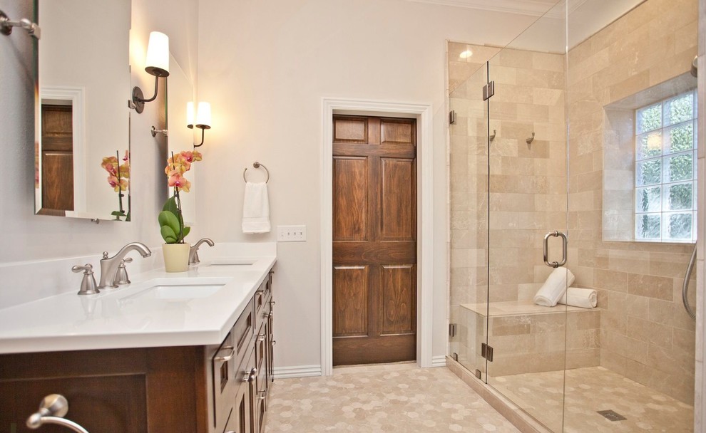 Example of a large transitional master ceramic tile and beige floor alcove shower design with recessed-panel cabinets, brown cabinets, a one-piece toilet, white walls, an undermount sink, quartzite countertops and a hinged shower door