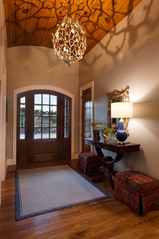 Example of a small transitional medium tone wood floor and brown floor foyer design with brown walls and a brown front door