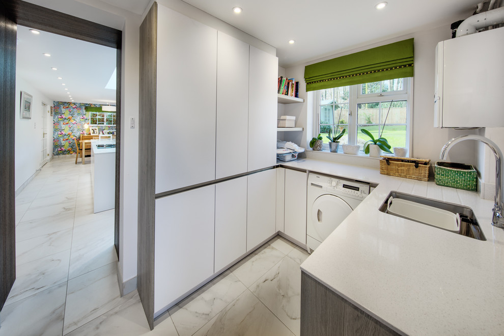 Photo of a small contemporary u-shaped utility room in Hampshire with a single-bowl sink, flat-panel cabinets, white cabinets, quartz benchtops, ceramic floors and white benchtop.