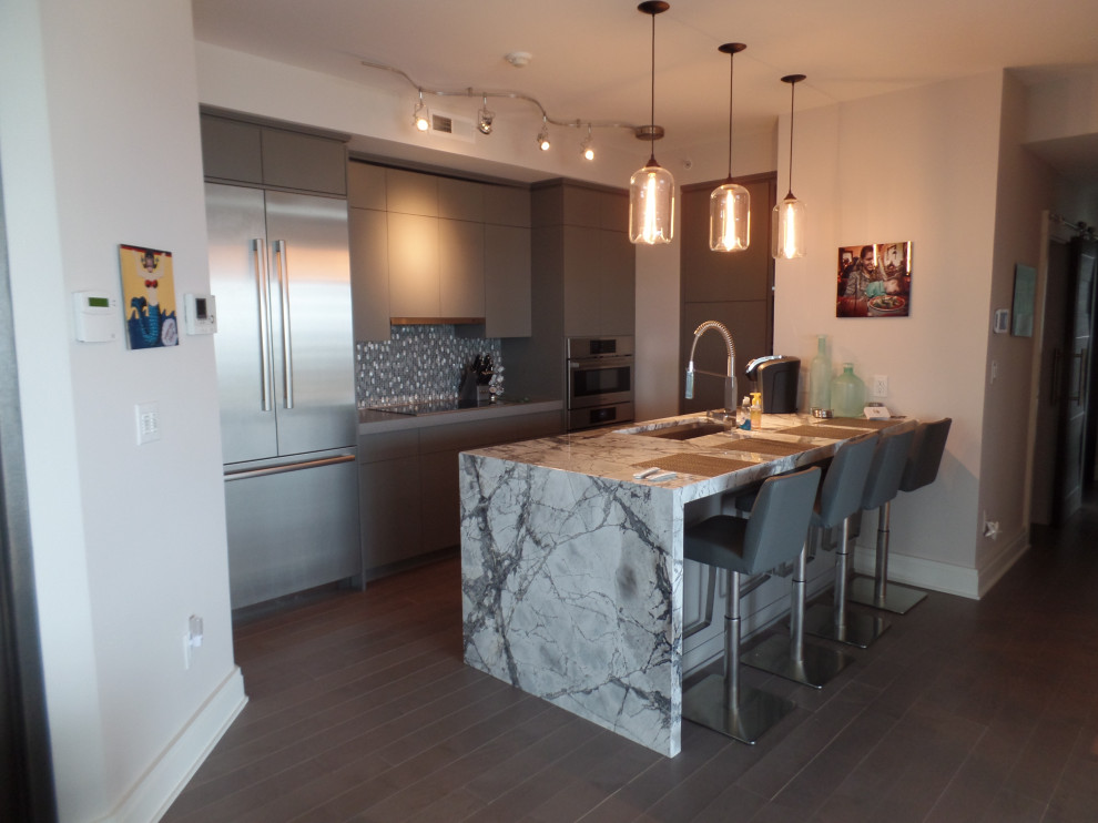 Eat-in kitchen - mid-sized contemporary l-shaped dark wood floor and brown floor eat-in kitchen idea with an integrated sink, flat-panel cabinets, gray cabinets, marble countertops, gray backsplash, mosaic tile backsplash, stainless steel appliances, an island and gray countertops