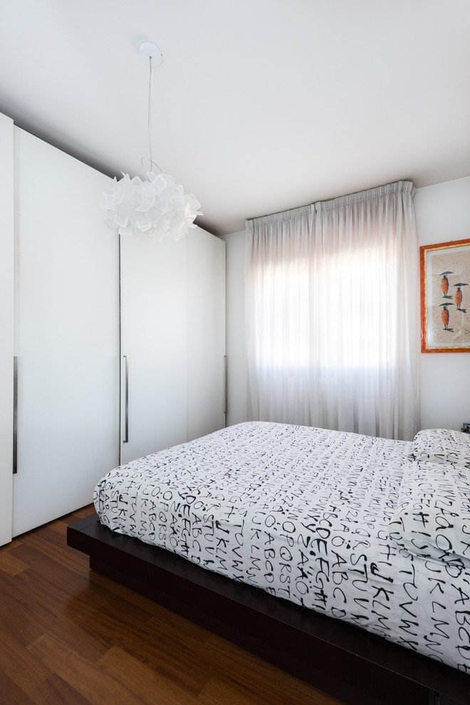 Modern master bedroom in Rome with white walls, medium hardwood floors and no fireplace.