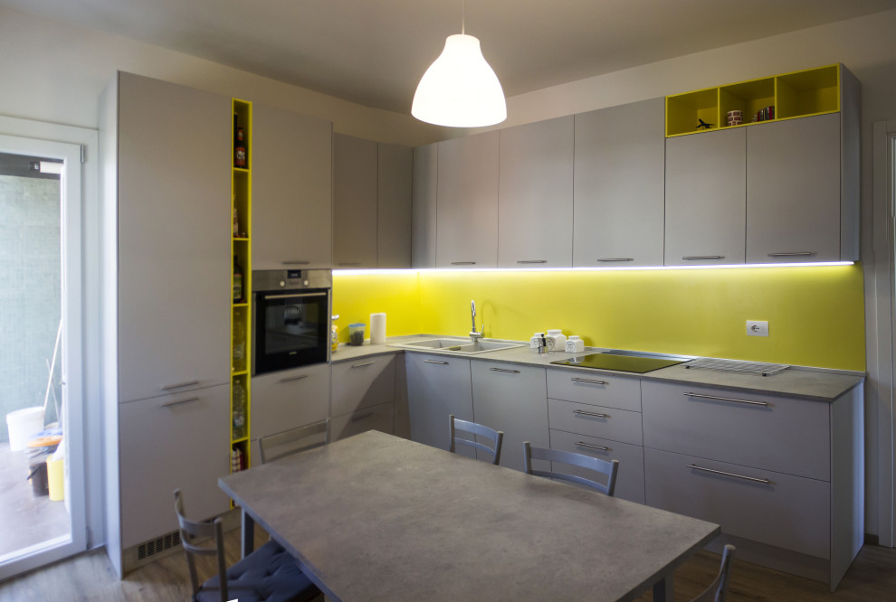 Inspiration for a mid-sized contemporary l-shaped separate kitchen in Other with a drop-in sink, flat-panel cabinets, grey cabinets, laminate benchtops, yellow splashback, laminate floors, no island and grey benchtop.
