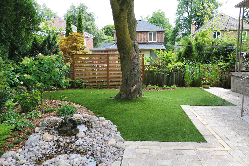 Photo of a large contemporary xeriscape in Toronto with with pond and concrete pavers.