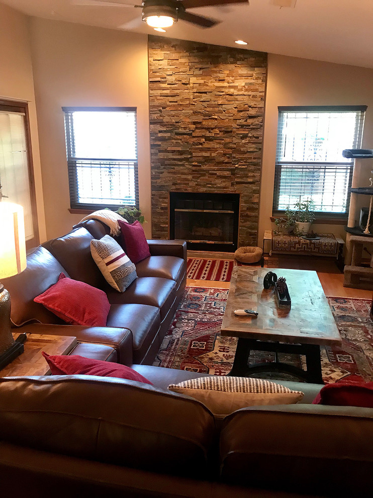 Inspiration for a mid-sized transitional open concept living room in Albuquerque with a standard fireplace, a stone fireplace surround, red walls, light hardwood floors, a freestanding tv and brown floor.