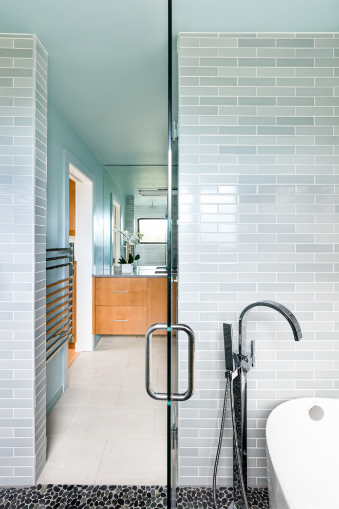 Photo of an eclectic wet room bathroom in Seattle with flat-panel cabinets, a freestanding tub, blue tile, ceramic tile, pebble tile floors, an undermount sink, engineered quartz benchtops, black floor, a hinged shower door and grey benchtops.