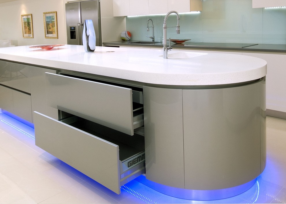 Design ideas for a mid-sized modern l-shaped open plan kitchen in London with a single-bowl sink, flat-panel cabinets, white cabinets, solid surface benchtops, blue splashback, glass sheet splashback, stainless steel appliances, porcelain floors and with island.