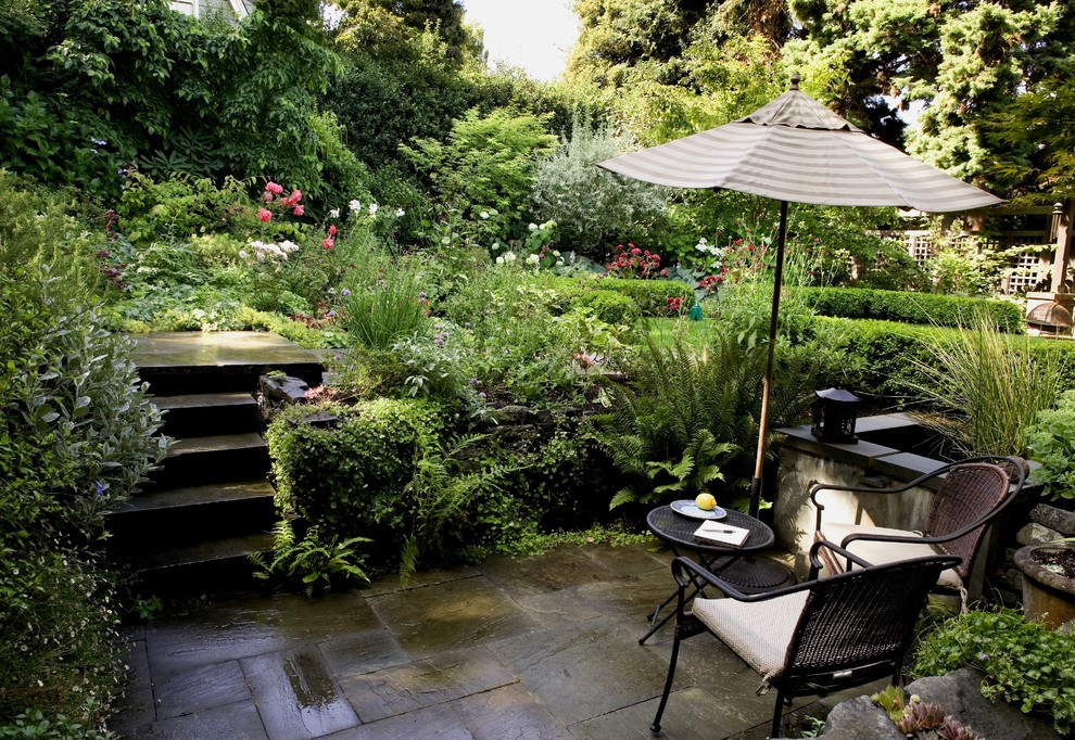 This is an example of a traditional backyard shaded garden for summer in Seattle with natural stone pavers.