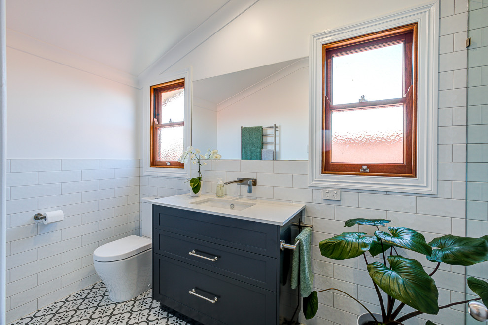 Cette image montre un WC et toilettes de taille moyenne avec un placard à porte shaker, un carrelage blanc, un plan de toilette en quartz modifié, un plan de toilette blanc et meuble-lavabo sur pied.