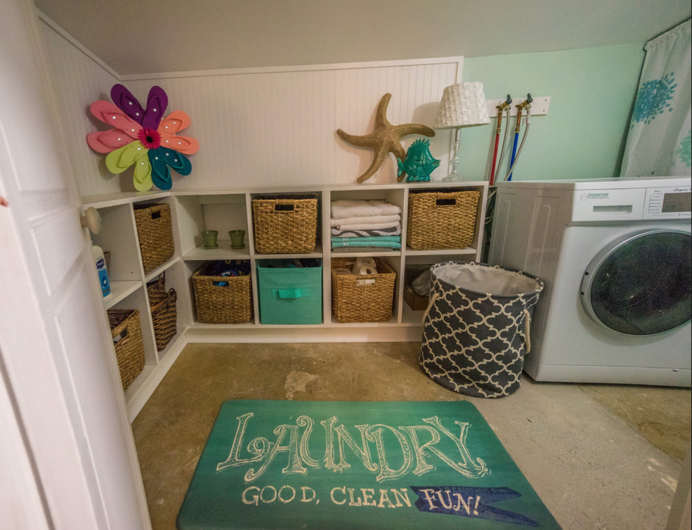 Small beach style l-shaped dedicated laundry room in Other with open cabinets, white cabinets, laminate benchtops, green walls, concrete floors and grey floor.