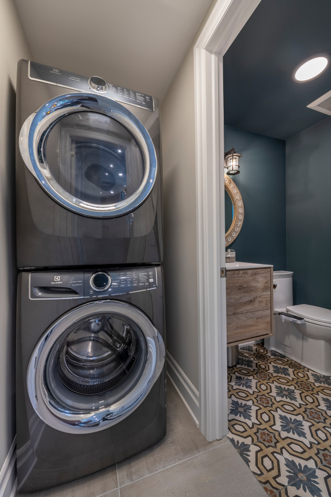 This is an example of a small contemporary single-wall utility room in Toronto with beige walls, porcelain floors, a stacked washer and dryer and beige floor.