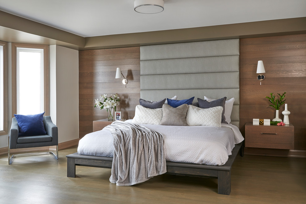 Large contemporary master bedroom in Toronto with beige walls, medium hardwood floors, a hanging fireplace, a metal fireplace surround and brown floor.