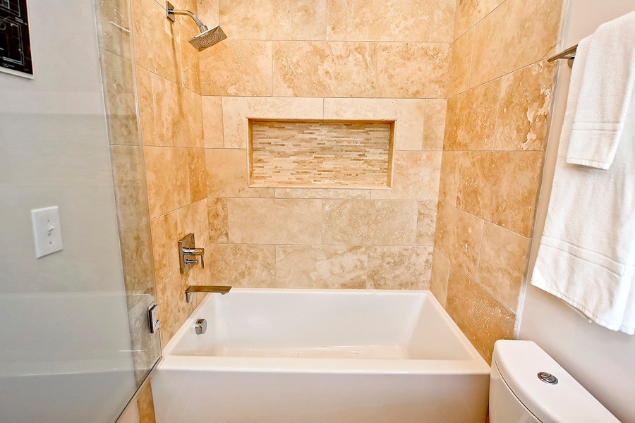 Small traditional 3/4 bathroom in DC Metro with a two-piece toilet, beige walls, porcelain floors, an alcove tub, a shower/bathtub combo, beige tile and porcelain tile.