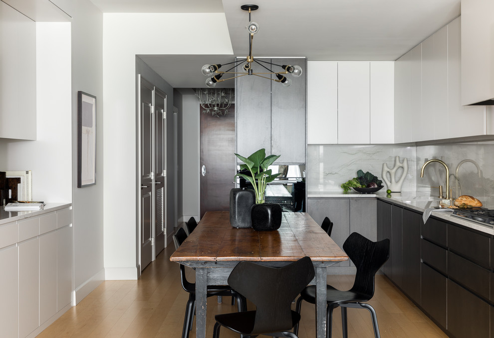 This is an example of a mid-sized contemporary l-shaped eat-in kitchen in Seattle with an undermount sink, flat-panel cabinets, quartzite benchtops, stone slab splashback, panelled appliances, no island, grey cabinets, grey splashback, medium hardwood floors, brown floor and grey benchtop.