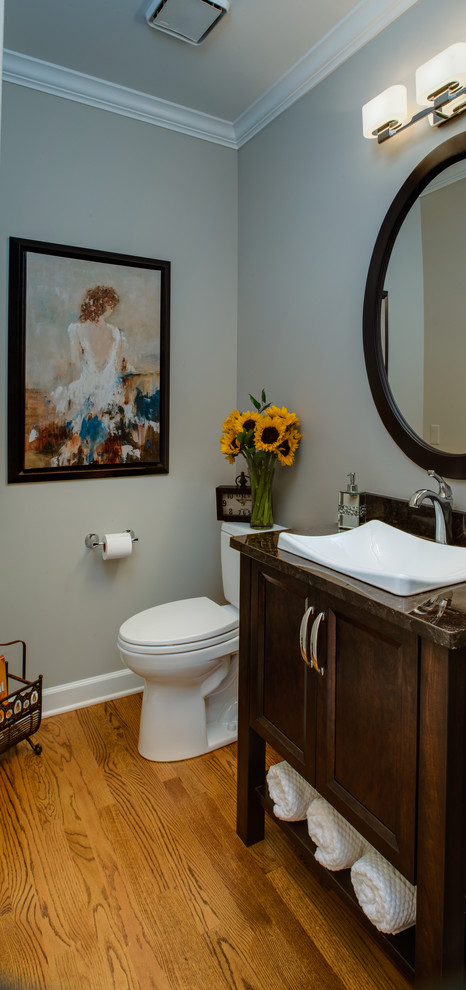 Design ideas for a mid-sized transitional powder room in Detroit with a vessel sink, recessed-panel cabinets, dark wood cabinets, granite benchtops, a two-piece toilet, grey walls and medium hardwood floors.