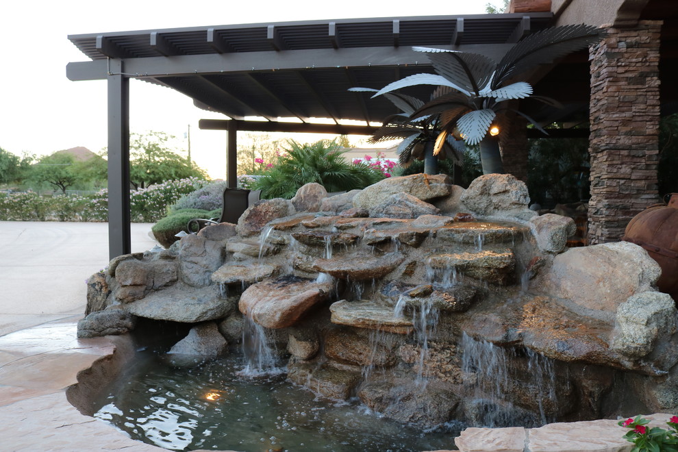 This is an example of a mid-sized rustic backyard stone water fountain landscape in Phoenix.