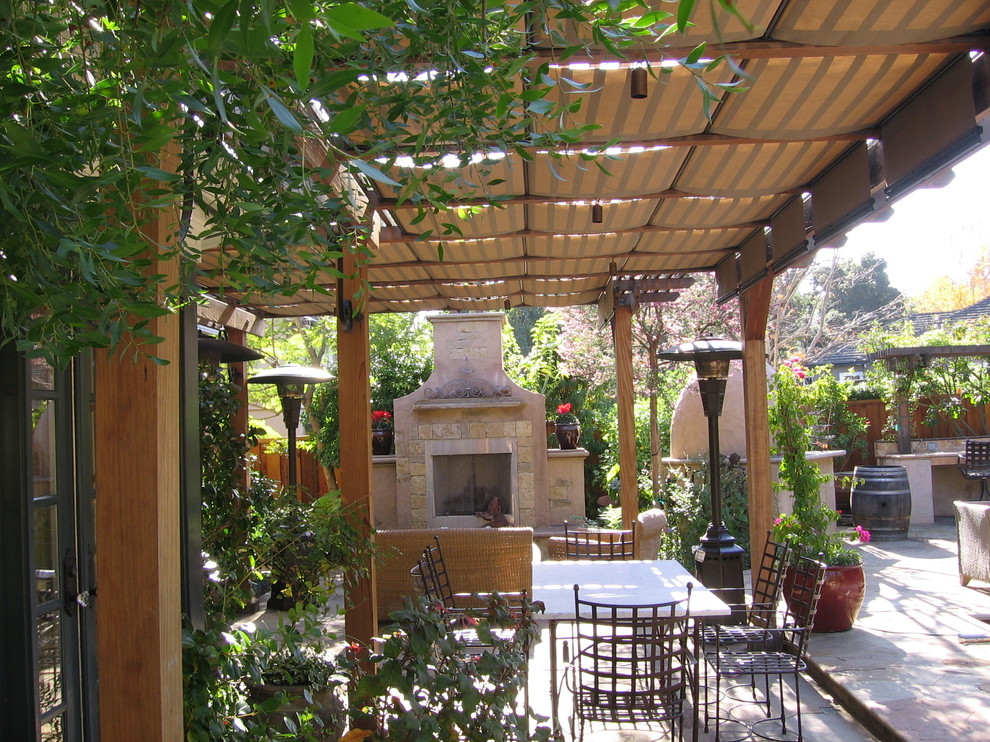 This is an example of a mid-sized traditional backyard patio in San Francisco with an outdoor kitchen, natural stone pavers and a pergola.