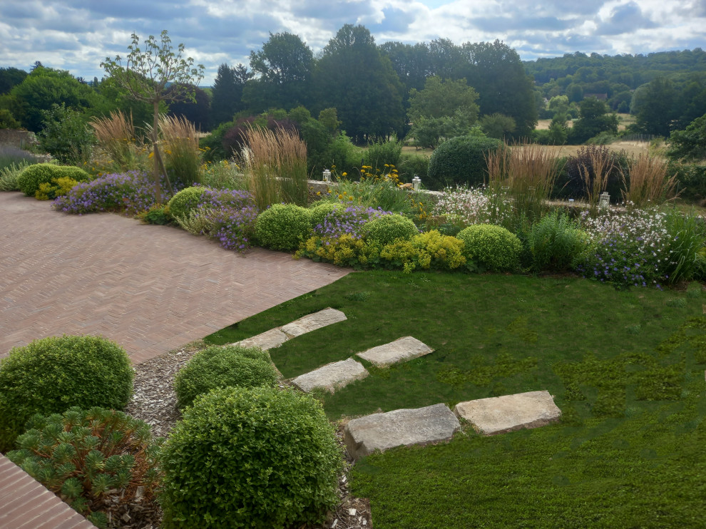 Landhaus Garten mit Blumenbeet, direkter Sonneneinstrahlung und Pflastersteinen