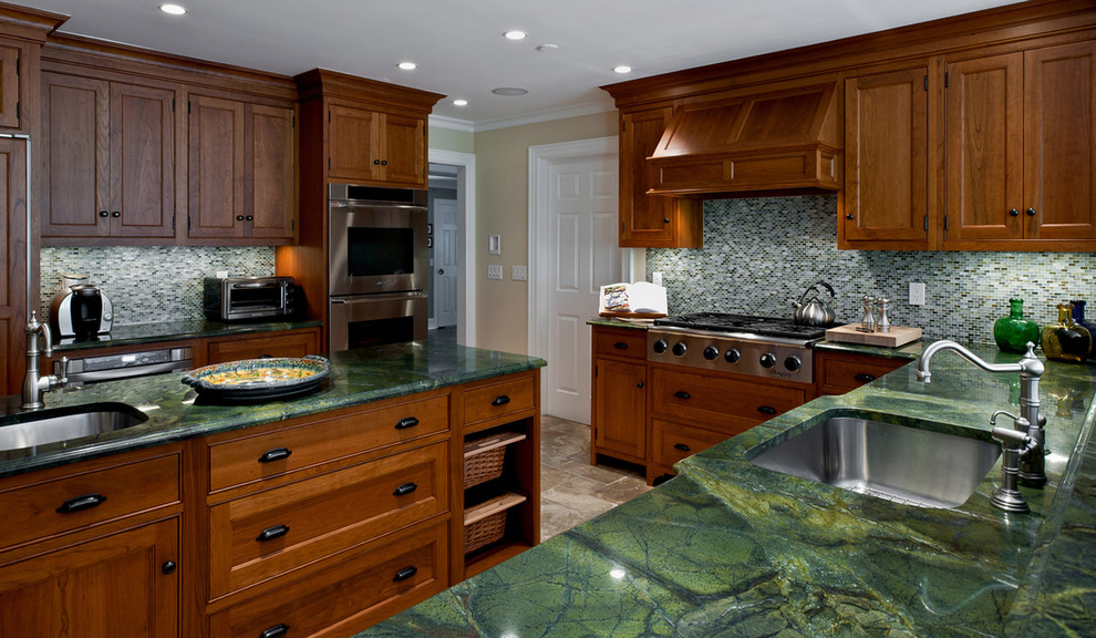 This is an example of a traditional kitchen in New York with mosaic tile splashback, stainless steel appliances, an undermount sink, recessed-panel cabinets, dark wood cabinets and green benchtop.