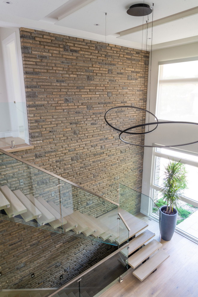 Inspiration for a large modern wood l-shaped glass railing staircase in Toronto with open risers and brick walls.