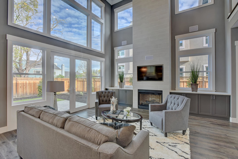 Large contemporary open concept family room in San Francisco with grey walls, medium hardwood floors, a standard fireplace, a tile fireplace surround, a built-in media wall and grey floor.