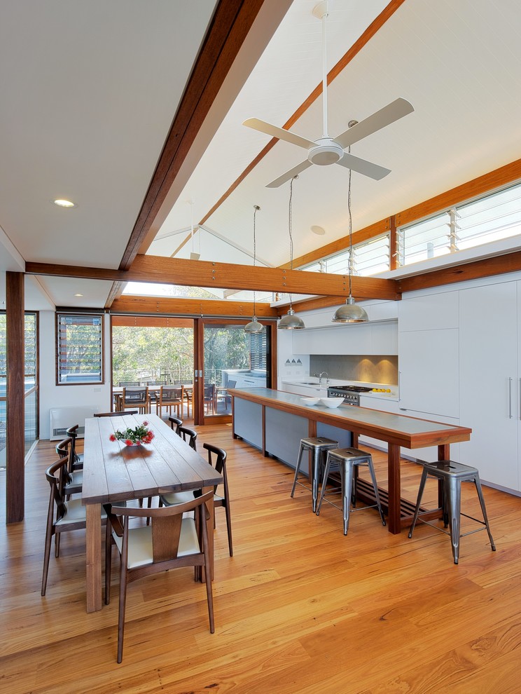 Photo of a contemporary galley eat-in kitchen in Sydney with zinc benchtops, medium hardwood floors, with island and flat-panel cabinets.