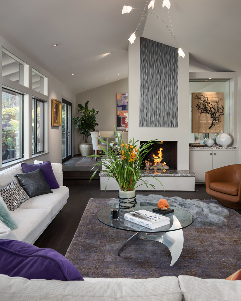 Design ideas for a mid-sized contemporary open concept living room in Orange County with grey walls, dark hardwood floors, a standard fireplace, a plaster fireplace surround, no tv and brown floor.