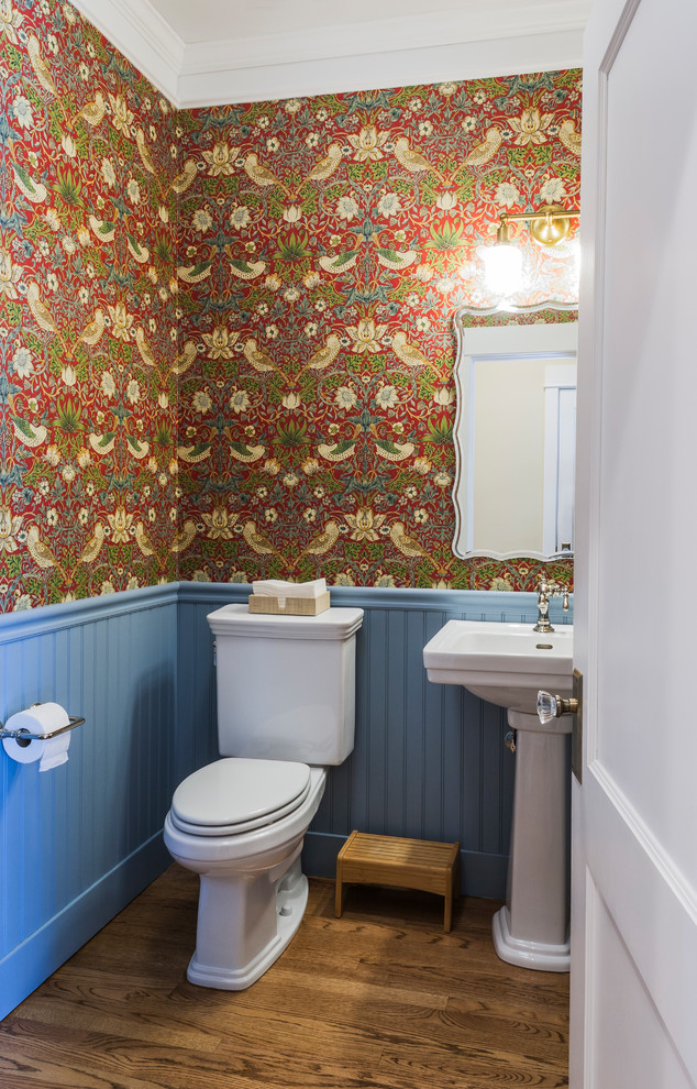 Example of a mid-sized farmhouse medium tone wood floor and brown floor powder room design with a two-piece toilet, blue walls and a pedestal sink