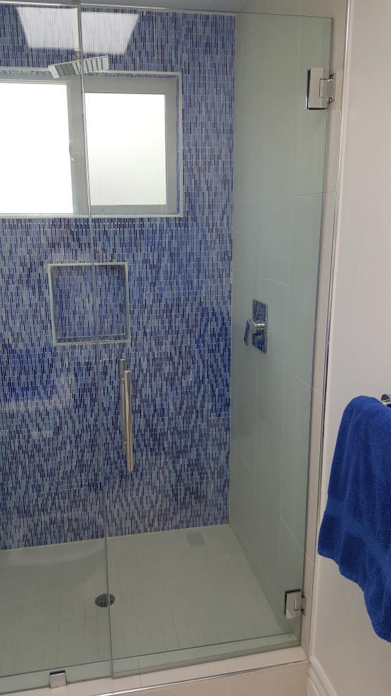 This is an example of a small contemporary bathroom in Los Angeles with white cabinets, blue tile, glass tile, white benchtops and a single vanity.